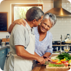 A senior couple cook together in a bright kitchen. 
